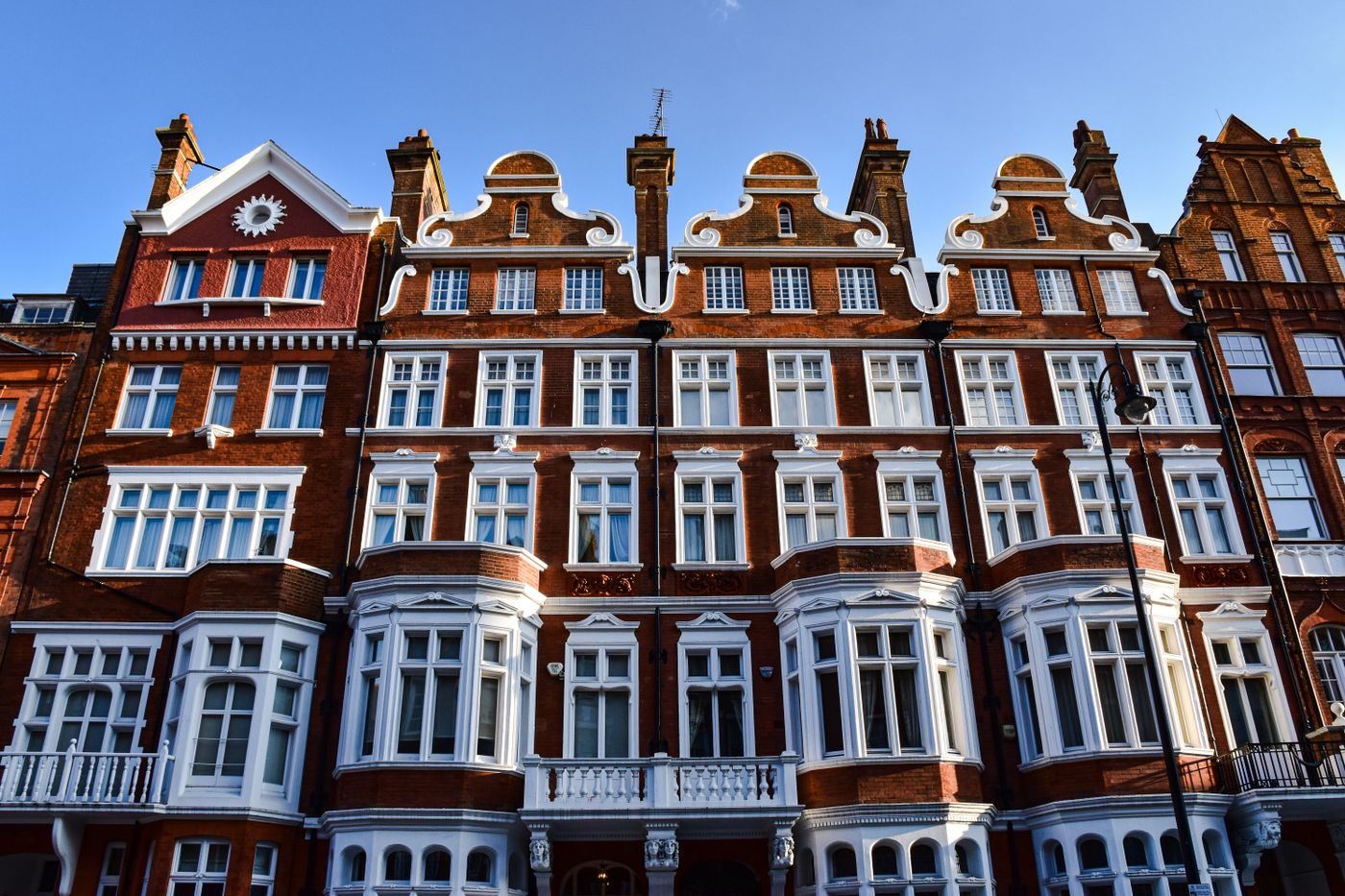 Red brick Victorian mansion block with white bay windows in London