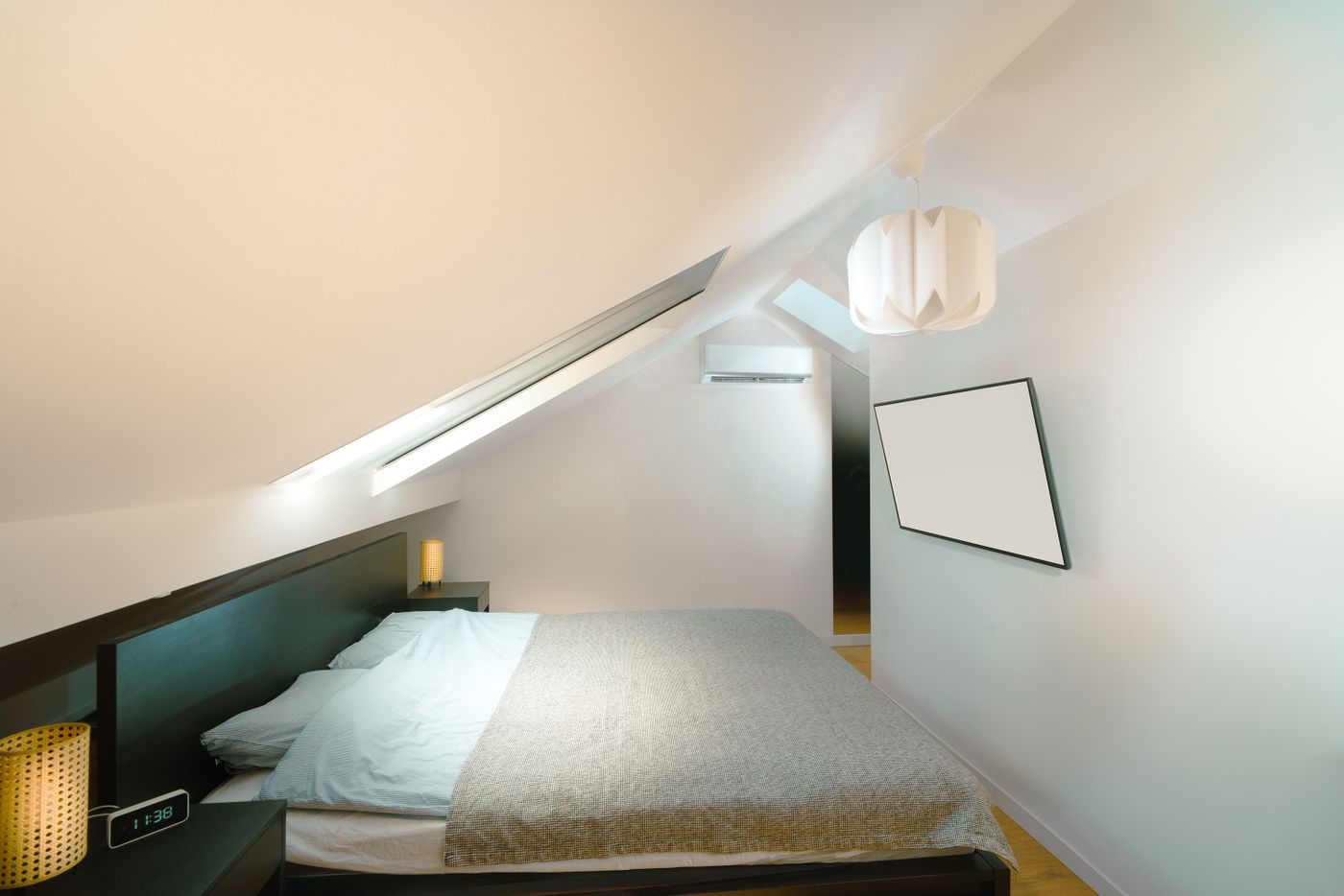 Loft bedroom with a sloping ceiling and a wall mounted air conditioner on the end wall